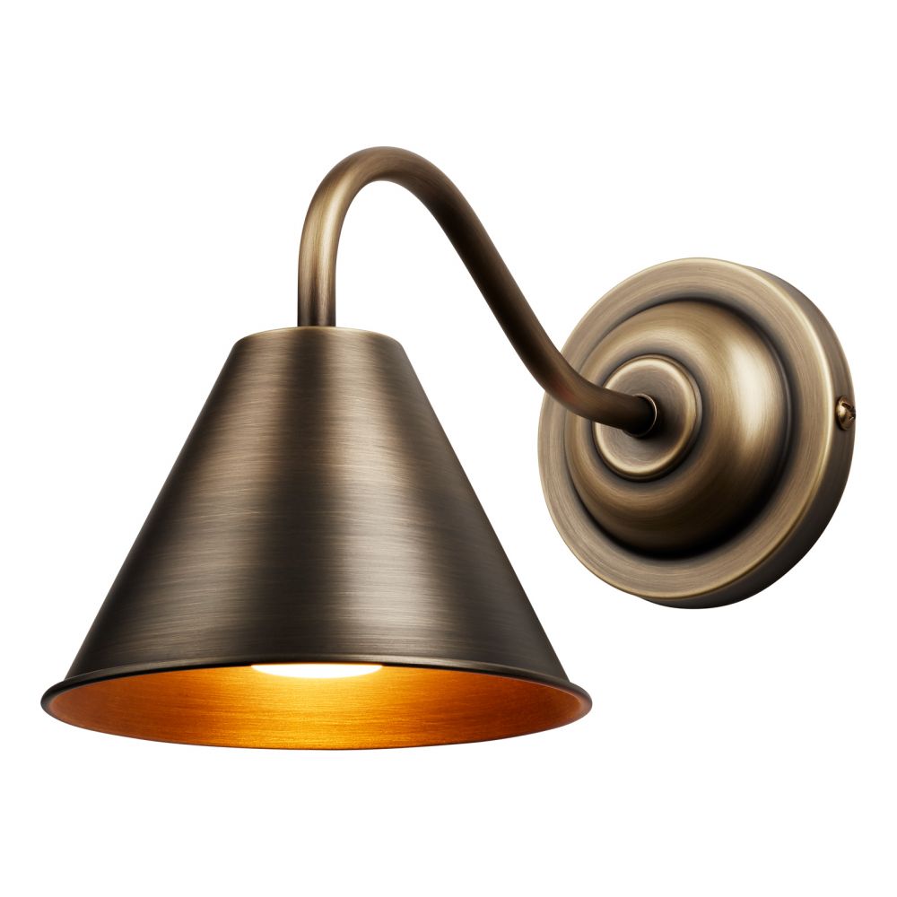 A bathroom wall light with a circular backplate finished in a matt soft bronze, from the back plate a curved arm comes off to hold a cone shaped shade which fans out from the arm pointing downwards